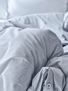 an unmade bed with white sheets and pillows