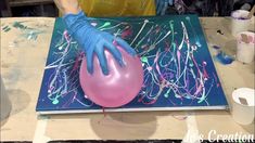 a person with blue gloves is painting on a large pink balloon in the middle of a table