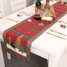 the table is set for christmas dinner with place settings and wine bottle on it,