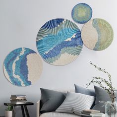 three circular wall hangings on the wall above a couch in a living room with pillows