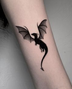 a small black dragon tattoo on the arm