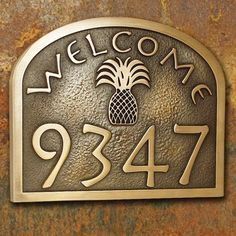 a welcome sign with a pineapple on it and the number 947 in gold