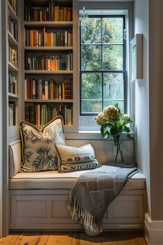 a window seat in front of a book shelf filled with books