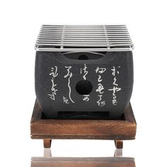 a small black and white object with writing on it's back end, sitting on a wooden stand