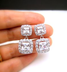 AAA cubic zirconia diamond square shape drop. Sparkling square cubic zirconia deco white gold plated metal frame post earrings.earrings have Emerald cut & Cubic Zirconia framed in micropave to look like real diamonds! Posts are sterling silver. Size: 2.7cm x 1.3cm Matching bracelet: https://www.etsy.com/listing/175833758/wedding-jewelry-bridesmaid-jewelry?ref=shop_home_active_7&ga_search_query=bracelet Matching necklace: https://www.etsy.com/listing/177502034/wedding-necklace-bridal-neck Elegant Silver Rectangular Diamond Earrings, Rectangular Cubic Zirconia Earrings For Gifts, Square Cut Jewelry With Diamond Accents For Wedding, Rectangular Cubic Zirconia Earrings As Gift, Rectangular Cubic Zirconia Earrings With Diamond Accents, Elegant Square Cut Jewelry With Diamond Accents, Elegant Rectangular Cubic Zirconia Earrings, Elegant Square Cut Cubic Zirconia Earrings, Elegant Square Pendant Jewelry For Wedding