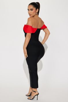 a woman in a black and red dress with her hands on her hips, posing for the