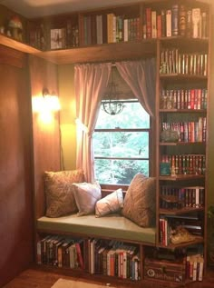 a window seat in front of a book shelf filled with books