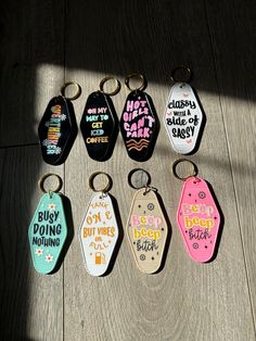 six keychains with sayings on them sitting on a wooden floor next to a window