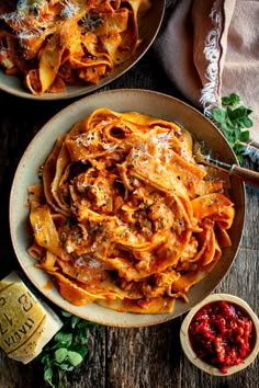 two bowls filled with pasta and sauce on top of a wooden table