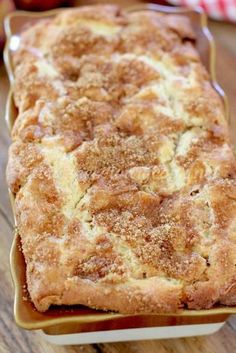 a loaf of bread sitting on top of a wooden table next to an apple pie