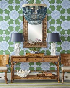 a table with two lamps and a mirror on it in front of a green wall