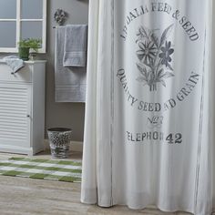 a white shower curtain with an old fashioned sign on it's side in a bathroom