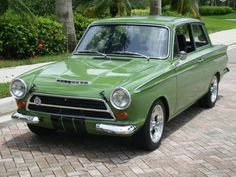 an old green car is parked on the street