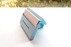 an origami box sitting on top of a table next to some grass and trees