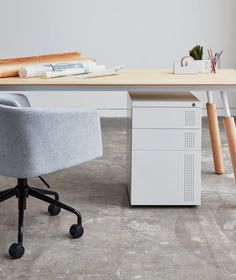 an office chair sitting next to a desk with a file cabinet on it and some books