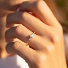 a close up of a person wearing a gold ring with an opal stone on it