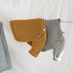 two knitted sweaters hanging on a clothesline next to a pair of pants