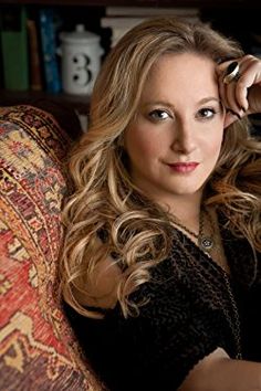 a woman sitting on top of a couch next to a book shelf