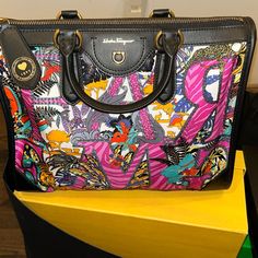 The Graffiti-Influenced Safari Printed Gancini Bag Is Crafted From Regenerated Nylon And Leather Trim Designer Multicolor Bag With Removable Pouch, Designer Multicolor Shoulder Bag With Top Carry Handle, Designer Multicolor Shoulder Bag With Top Handle, Designer Multicolor Double Handle Bags, Designer Multicolor Travel Bags, Designer Multicolor Satchel With Top Carry Handle, Designer Multicolor Shoulder Bag With Handles, Luxury Multicolor Shoulder Bag With Top Carry Handle, Luxury Multicolor Satchel With Top Carry Handle