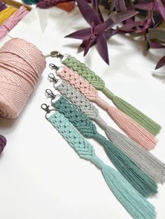 several crochet tassels are shown next to some yarn and purple flowers