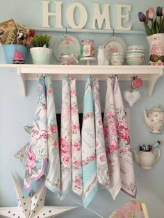 several tea towels hanging on a shelf in a room with blue walls and pink flowers