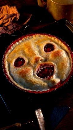 a pie with two faces on it sitting on top of a table next to utensils