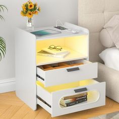 a night stand with two drawers and an electronic device on the top, next to a bed