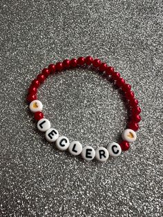 a red beaded bracelet with white letters on it