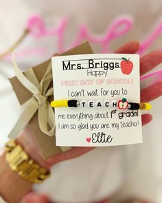 a hand holding a teacher appreciation card with two bracelets on it's wrist