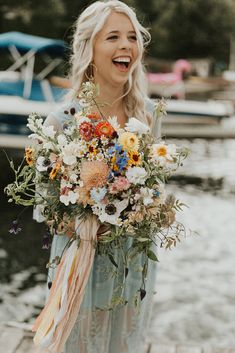 a woman standing on a dock holding a bouquet of flowers