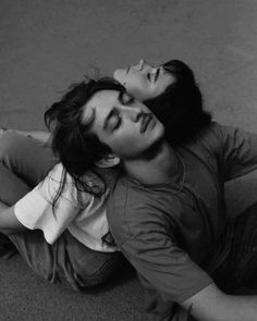 two people laying on the ground with their eyes closed