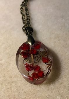 a glass ball with red flowers in it on a chain