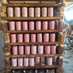 several rows of pink candles are arranged on a wooden shelf in front of other items