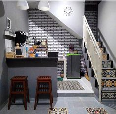 a kitchen with two stools next to the counter and stairs in front of it