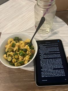 a bowl of pasta and a tablet on a table