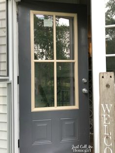 a gray front door with two windows and a welcome sign