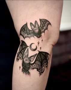 two bats with moon and stars tattoo on the legs, one is black and white