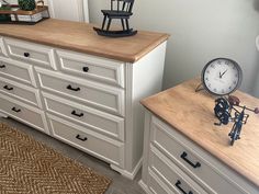 a white dresser sitting next to a clock on top of a wooden counter