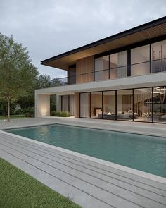 a large pool in front of a modern house with glass doors on the windows and an outdoor dining area