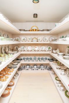 a room filled with lots of plates and bowls on shelves next to eachother