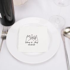 a white plate topped with a napkin next to silverware and wine glasses on top of a table