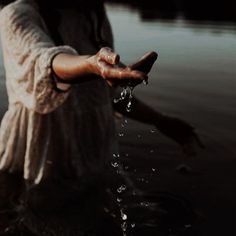 a woman is holding her hand out in the water