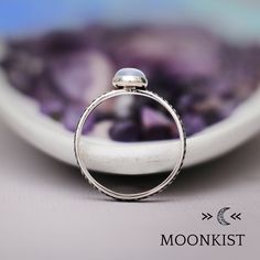 a close up of a ring on a plate with purple rocks in the back ground