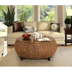 a living room filled with furniture and a coffee table on top of a rug in front of two windows