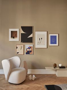 a living room with pictures on the wall and a chair in front of a table