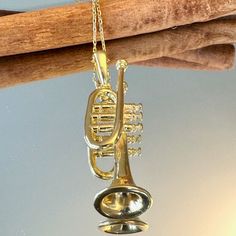 a brass musical instrument necklace hanging from a tree branch