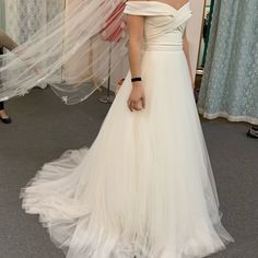 a woman in a wedding dress looking at herself in the mirror with her hand on her hip