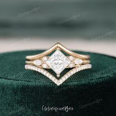 an engagement ring with a princess cut diamond in the center on top of a green velvet box