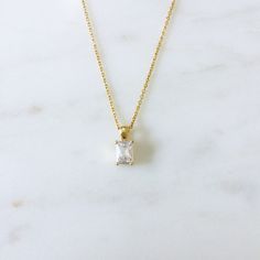 This is a dainty necklace with a small emerald cut CZ pendant. Perfect for everyday wear. Necklace Metal: 24K Gold filled Necklace Size: 16 in Pendant Metal : 18K Gold FilledPendant Size: 13 mm x 5 mm Pendant Stone: Cubic Zirconia Dainty Gold Baguette Cut Necklace, Gold Baguette Cut Solitaire Necklace, Timeless Gold Solitaire Necklace With Emerald Cut, Elegant Radiant Cut Yellow Gold Necklace, Timeless Gold Necklace With Emerald Cut, Cubic Zirconia Necklace With Rectangular Pendant For Anniversary, Dainty Cubic Zirconia Jewelry In Baguette Cut, Gold Emerald Cut Necklace For Everyday Use, Anniversary Cubic Zirconia Necklace With Rectangular Pendant