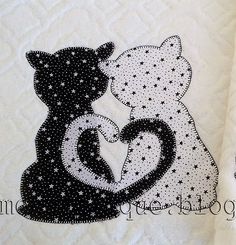 two towels with black and white cats on them, one holding the other's hand